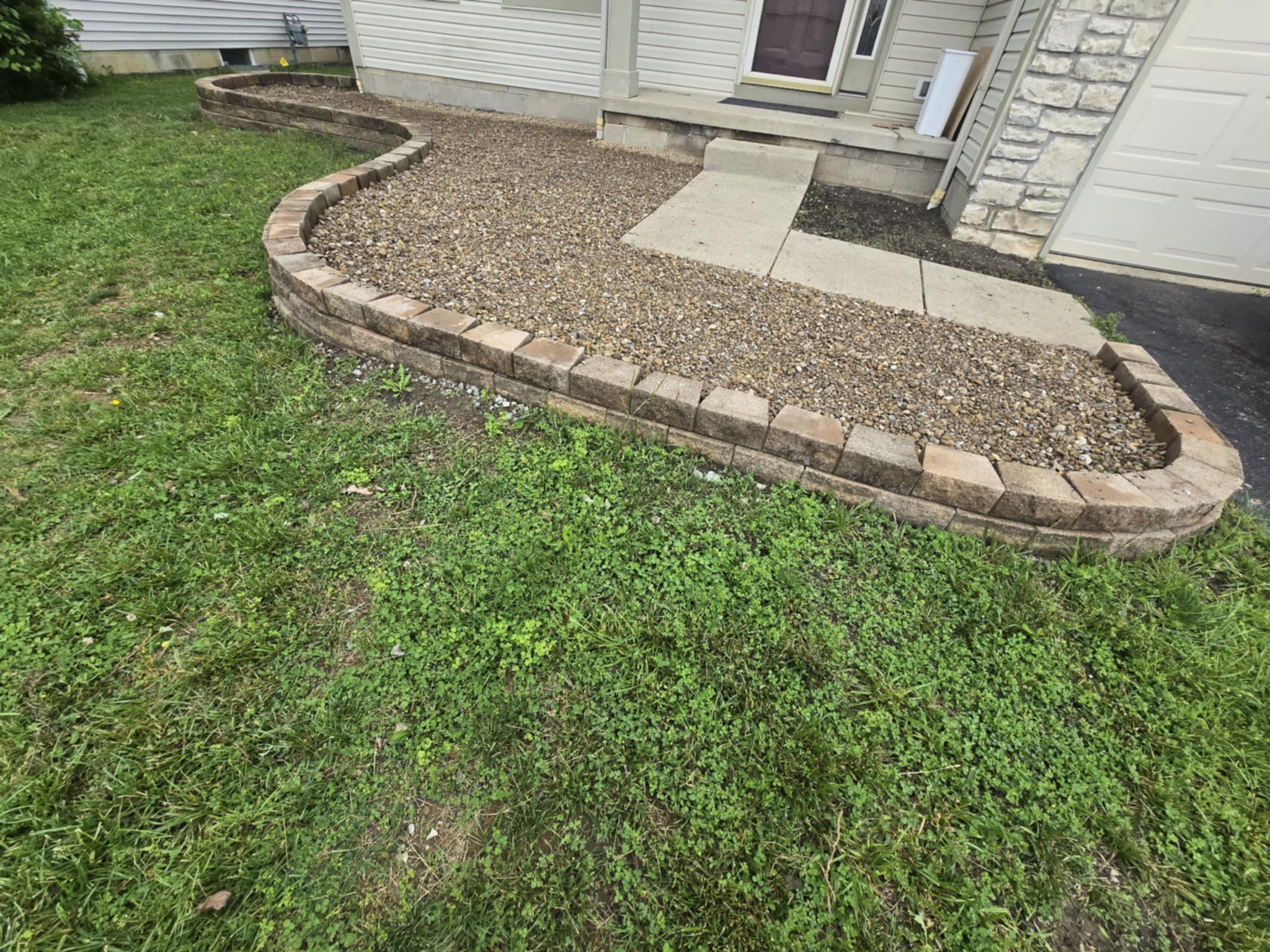Curved tumbled stone retaining wall with river rock ground cover